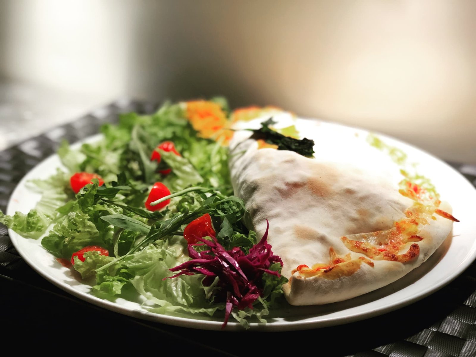 Calzone Rústico — massa de pizza recheada com chouriço, cogumelos, ovo e mozzarella, servido com salada